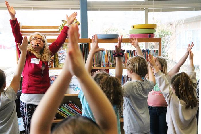 FLS Teacher Working With Students Holding Their Hands Up