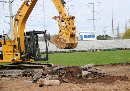 Construction crane removing some of the ground within a sports field