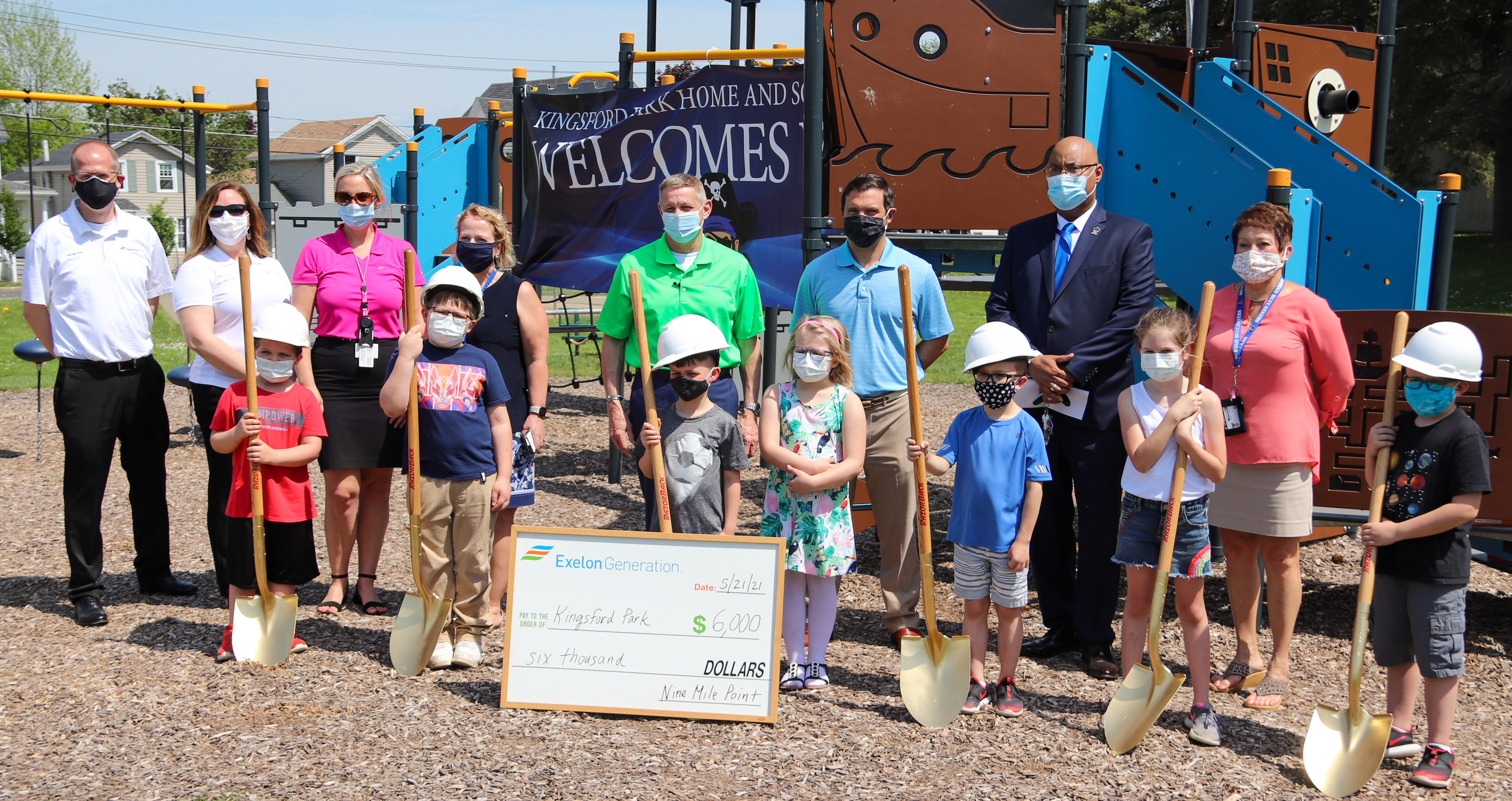 School Employees and Student Stand at the Newly Built KPS Playground with a Big Check on the Ground