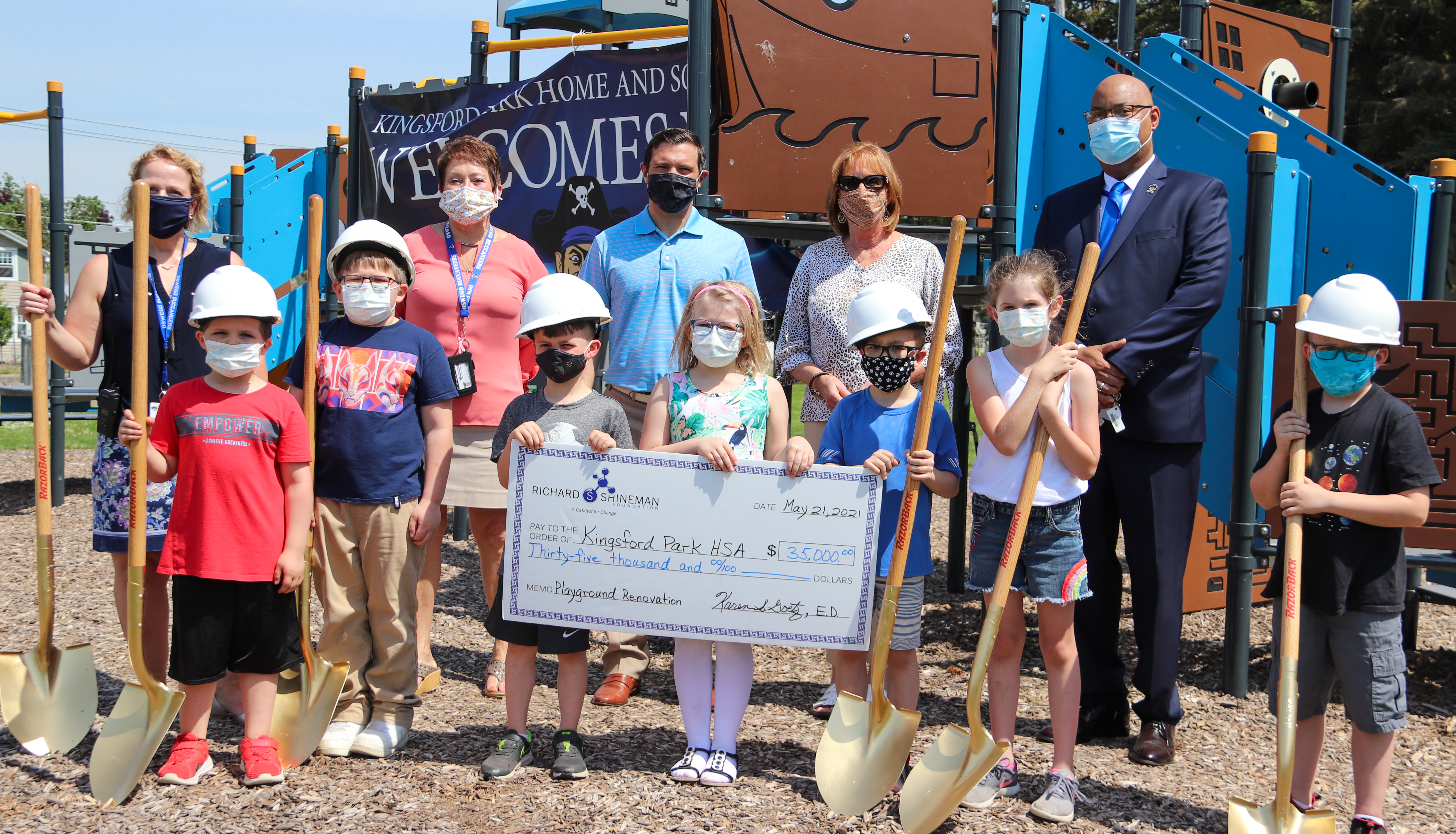 School Employees and Student Stand at the Newly Built KPS Playground with a Big Check in their Hands